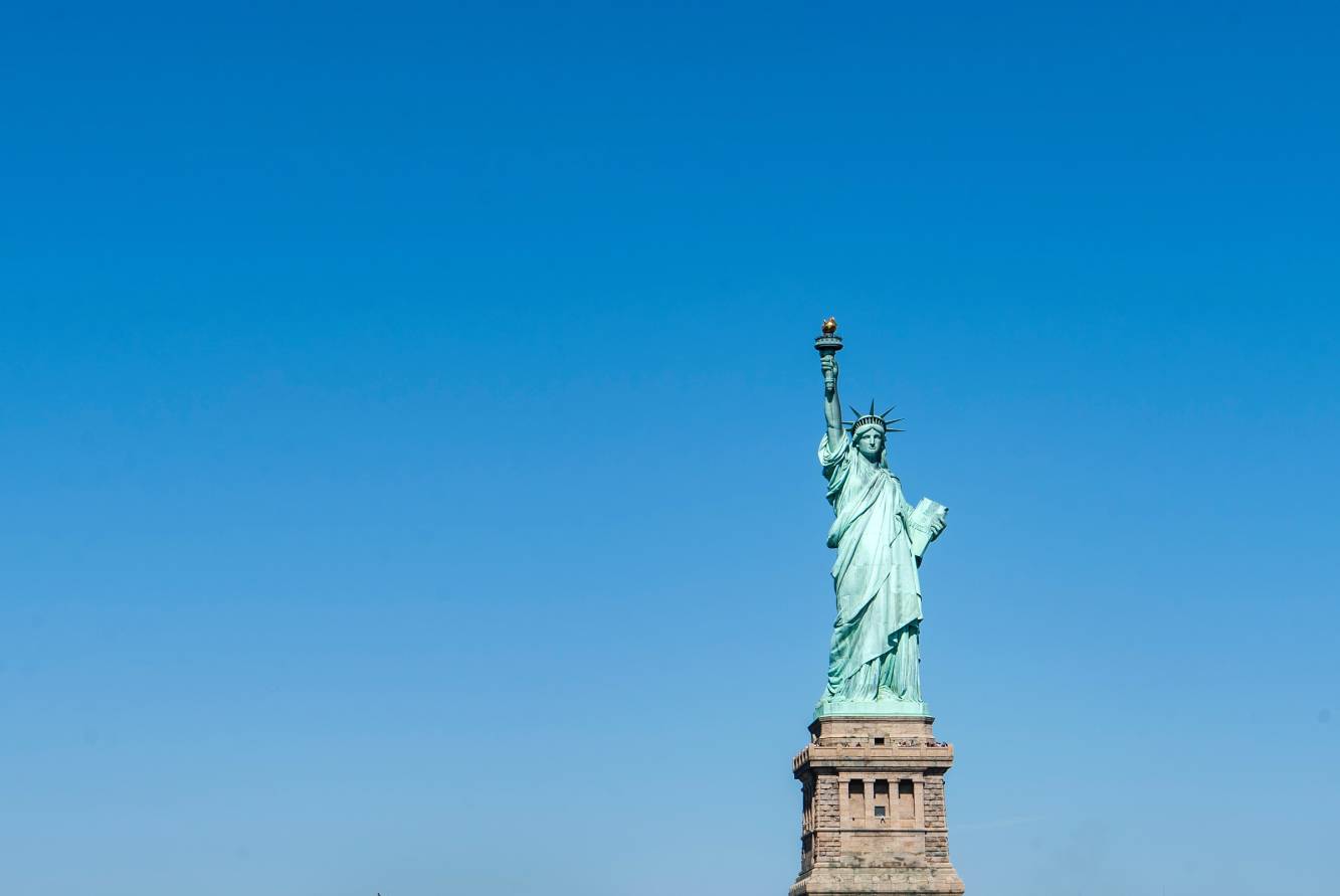 Clear blue sky background with Statue of Liberty in foreground.