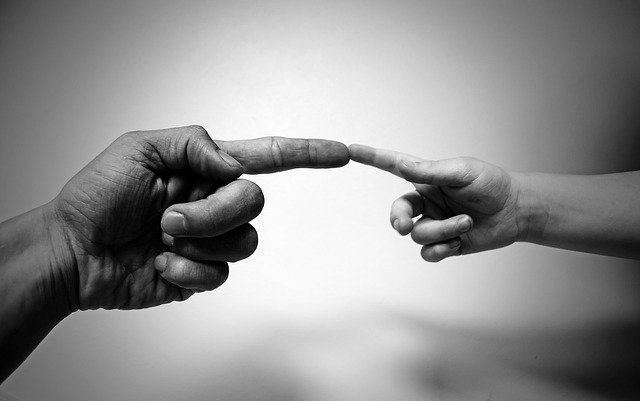 B&W of adult index finger touching child index finger, as if to say, "Caring".