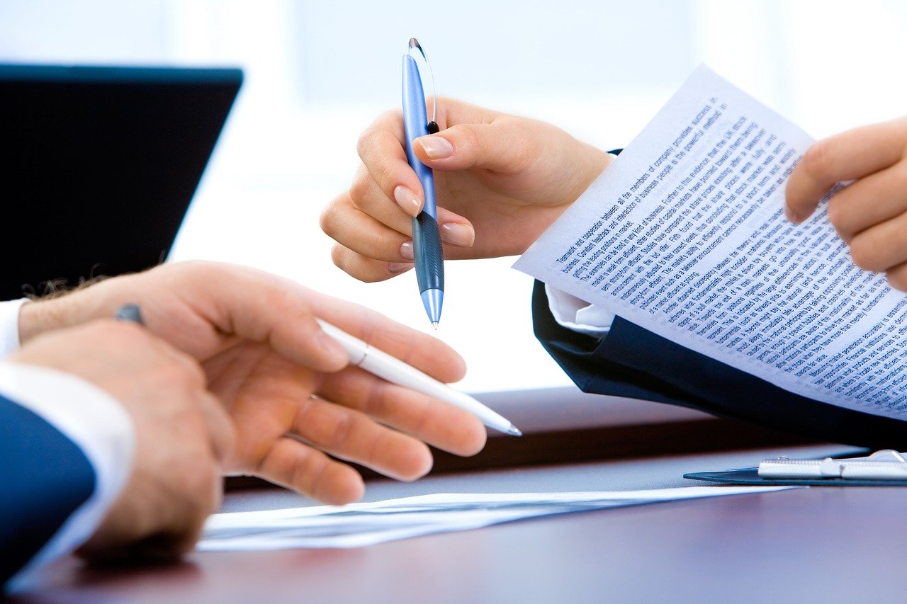 Business people at desk with pen and papers.